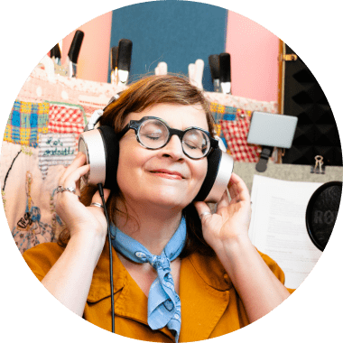 Martha Chang in her professional voiceover studio at Chick Creative, smiling and wearing headphones