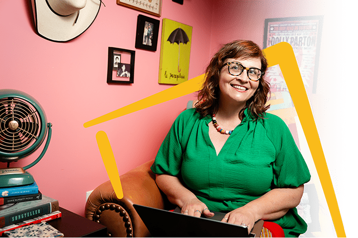 Martha Chang, freelance copywriter & voice talent, on the couch in her colorful Chick Creative workspace, smiling brightly